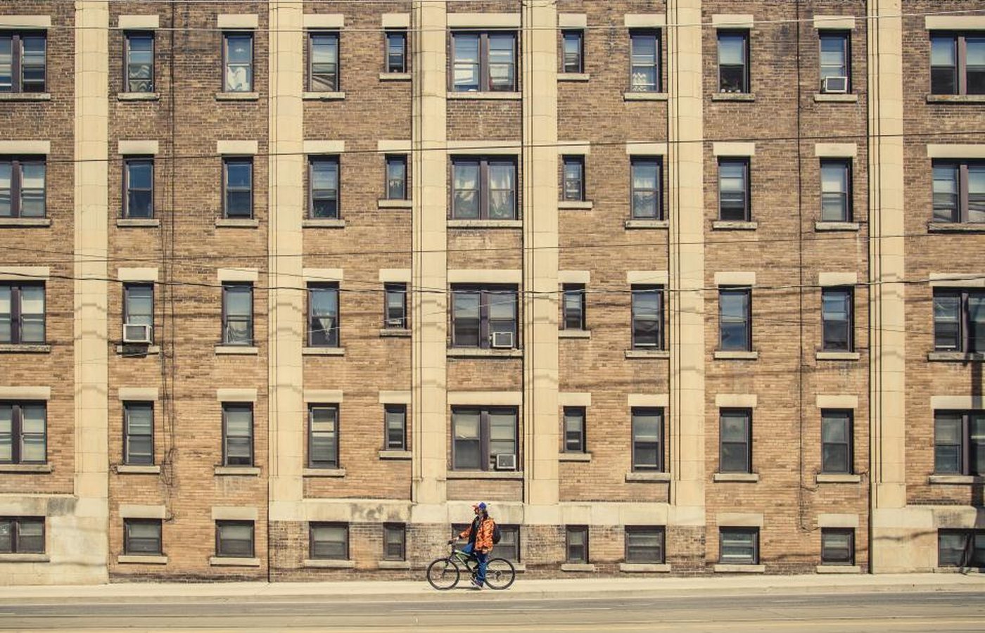 A brick apartment building with a cyclist passing on the street