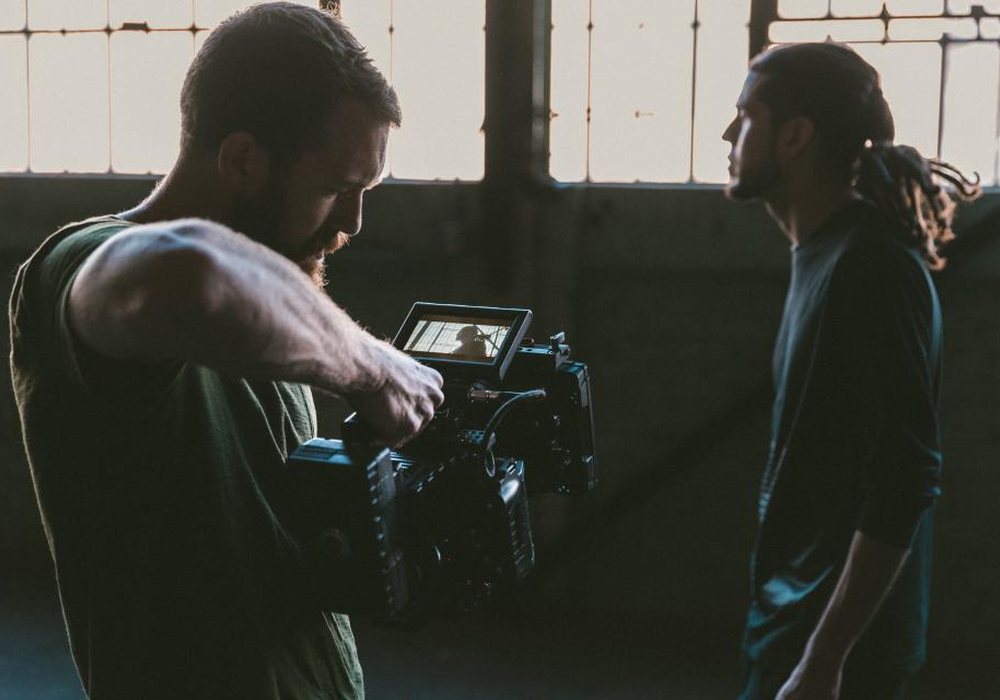 A camera operator filming a subject in a warehouse